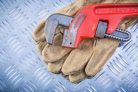 Leather protective gloves monkey wrench on corrugated metal background construction concept