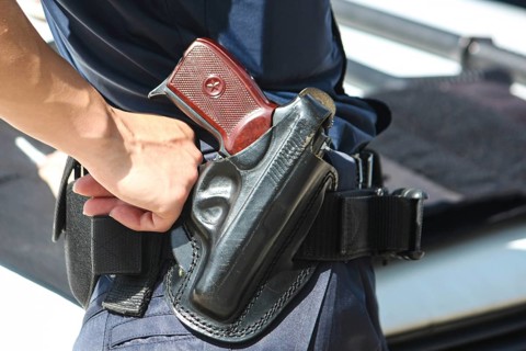 A woman's hand touches a body and a gun. Woman with a gun. Woman policemen with gun in a black