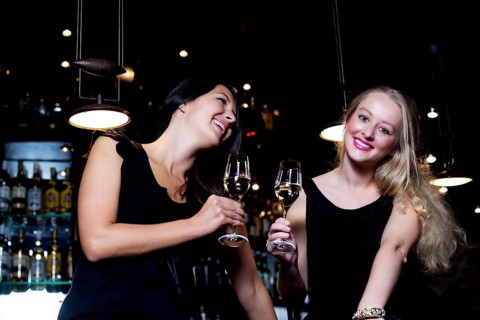 Two beautiful young women sharing their friendship and celebrating with champagne, in a fancy