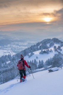 Pretty active senior woman snowshoeing in the Allgäu Alps near Oberstaufen with a view of the