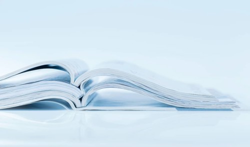 Stack of open magazines in blue tone on white background with copy space