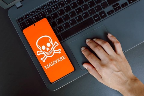 In this photo illustration, the Malware icon is displayed on a smartphone screen next to a person