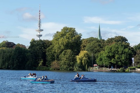 Leisure activities in summer, pedal boats against a blue sky on the Alster, with the Telemichel