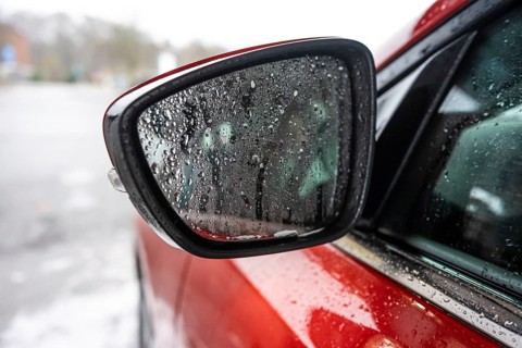 Fine water droplets on a side mirror of a red car