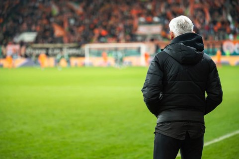 Head coach's back and soccer match at the stadium in the background