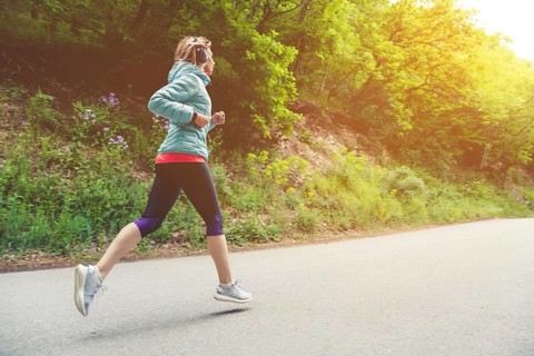 A young blonde woman running is practicing outdoors in a city mountain park in the forest. Warm