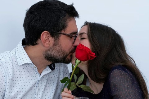 Young couple kissing with a red rose in front of them