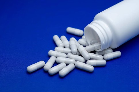 Large white pills fell from a large white bottle. Life without drugs and dependence on capsules of