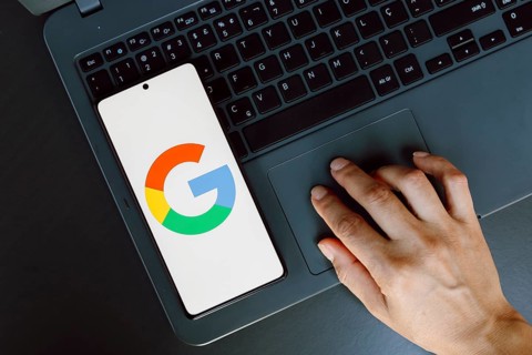 In this photo illustration, the Google logo is displayed on a smartphone screen next to a person