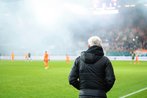 Head coach's back and soccer match at the stadium in the background