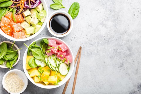 Two assorted poke bowls with raw fish and vegetables, space for text. Top view, close up. Hawaiian