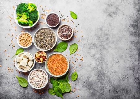Top view of different vegan protein sources with space for text: beans, lentils, quinoa, tofu,