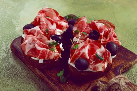 Sliced cured ham, sandwiches with prosciutto and black olives, Italian dish, delicacy, Parma ham,