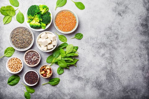 Top view of different vegan protein sources with space for text: beans, lentils, quinoa, tofu,