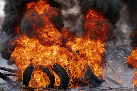 Burning automobile tires, strong flame of red fire and clouds of black smoke in sky. Selective