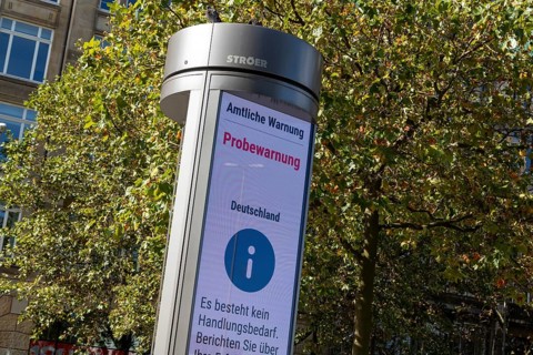 Symbolic image disaster control, advertising pillar with the display Official warning, test