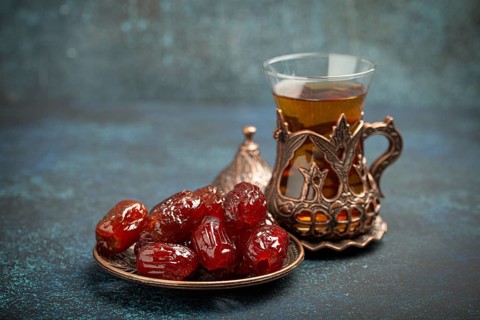 Breaking fasting with dried dates during Ramadan Kareem, Iftar meal with dates and Arab tea in
