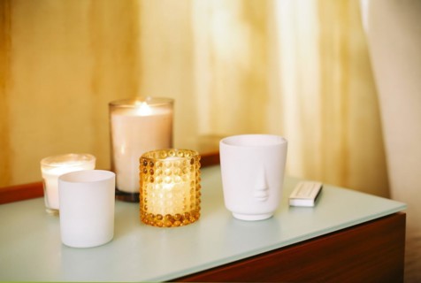 Table with many burning lighting scented candles and aromatic incense sticks in spa massage salon
