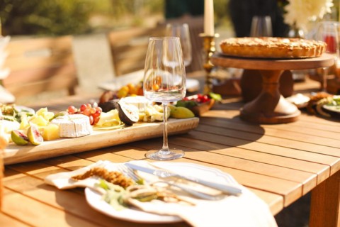 Empty wineglass placed near board with fruits on banquet table on sunny summer day