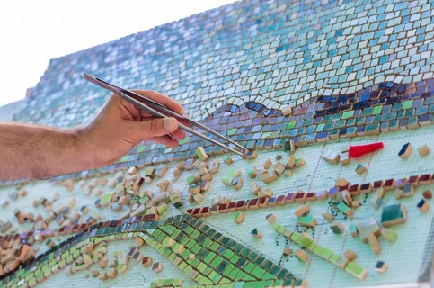 Mosaic as a ceramic or ceramic mosaic. The man organizes design with a tweezers a puzzle of ceramic