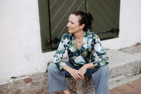 Smiling, dark-haired woman, 40+, sitting on a staircase