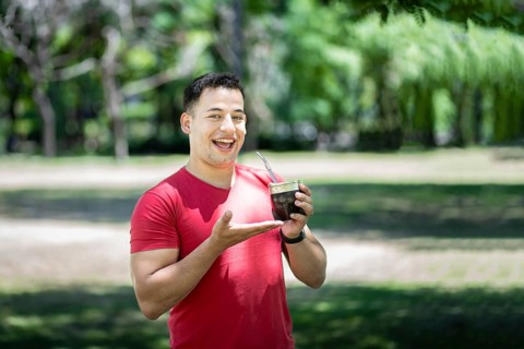Happy latin man showing his mate tea