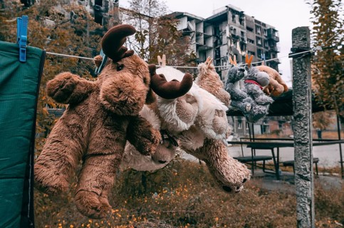 Soft toys are dried after washing against the background of a burnt-out multi-storey building in