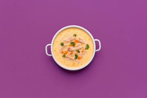 Top view with a bowl of chicken soup, greek recipe with lemon juice and vegetables