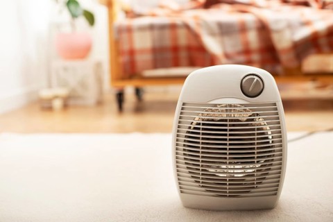 Fan heater on the floor in living room with sofa at background