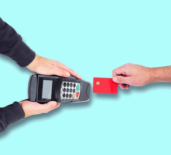top view of person paying using credit card or debit card, holding card against credit card reader