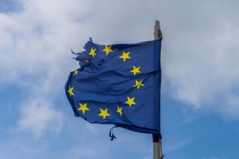 A torn EU flag blows in the wind with a few clouds in the background, seen in Pevensey Bay, East