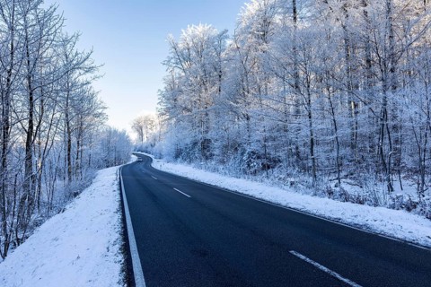 Snow-covered road winds through a wintry forest, hoarfrost in Unterallgäu, Bavaria, Germany, Europe