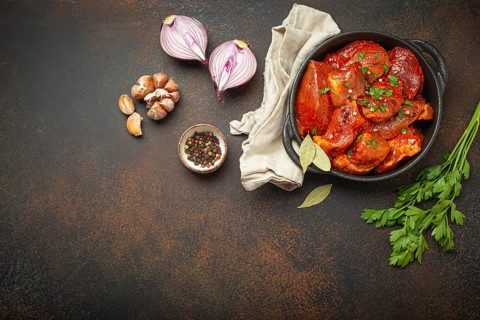 Cooking hearty meat stew. Raw uncooked chopped pieces of meat marinated with seasonings and parsley