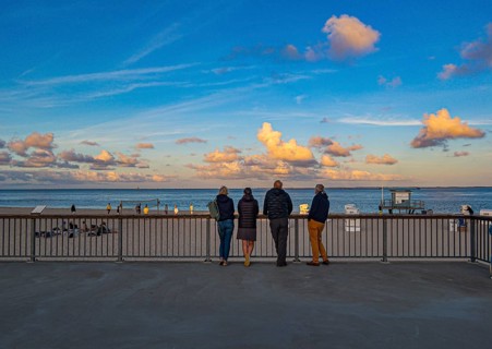 Holidaymakers stand on the promenade in the evening light and look out to sea, Hörnum, Sylt