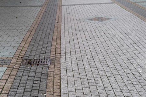 Deserted paved pedestrian zone with gully cover