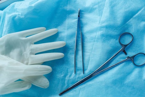 Surgical tools and gloves on blue cloth, showing readiness for medical procedures