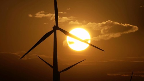 Beautiful sunrise dawn landscape with windmills or wind turbine on wind farm in rotation to