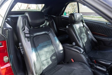 Spacious car interior with black leather seats and headrest, bathed in sunlight
