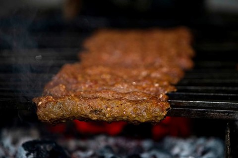 Making Spicy seekh kebabs are being grilled on burning charcoal in barbeque at a dinner party at