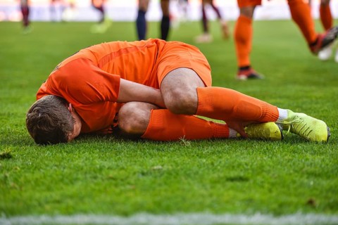 The injured footballer lies on the pitch.