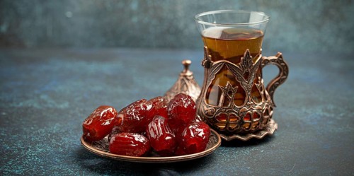 Breaking fasting with dried dates during Ramadan Kareem, Iftar meal with dates and Arab tea in