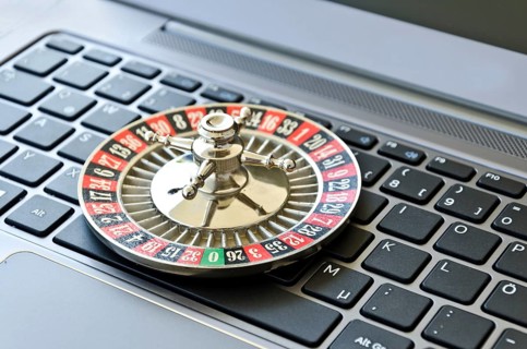 Roulette wheel lying on computer keyboard symbolizing online gambling