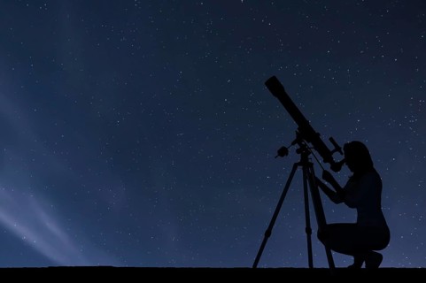 Girl looking at the stars with telescope. Starry night sky