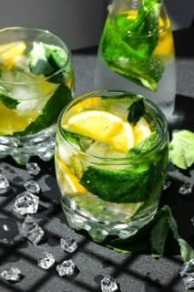 Mojito refreshing cocktail, alcohol drink. Lemonade with lemon and mint leaves on dark background.
