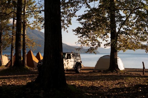 Tents and a white jeep with mountains in the background, sunrise at the lake, Shikotsu-Lakeside