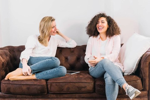 Cheerful women with technologies speaking sofa