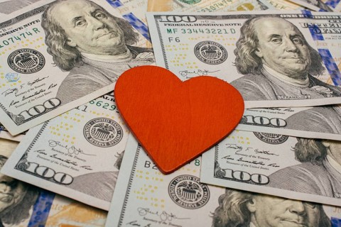 Red heart lies on dollar bills. Concept of selling love for money