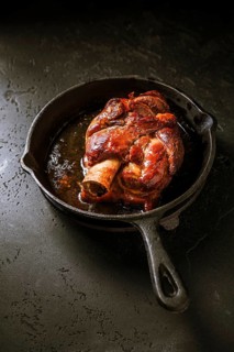 Traditional German cuisine - Roasted pork knuckle eisbein (Schweinshaxe) in iron pan on black