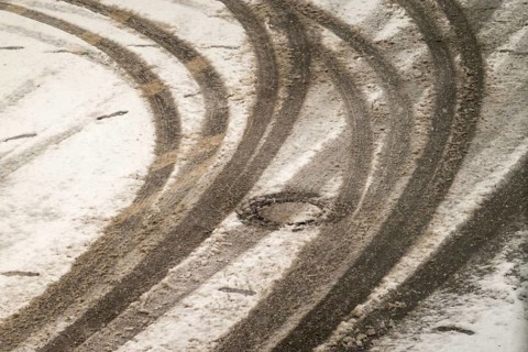 Car tire tracks curving on a snowy road surface in winter, indicating vehicle movement and winter