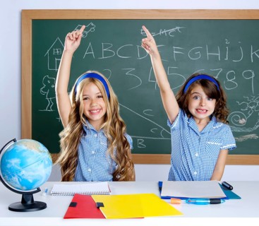 Smart students in classroom raising hand with blackboard
